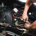 Auto technician working on a car's electrical system.