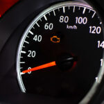 Car dashboard with check engine light illuminated.