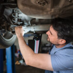 Auto mechanic working on suspension system of a car.