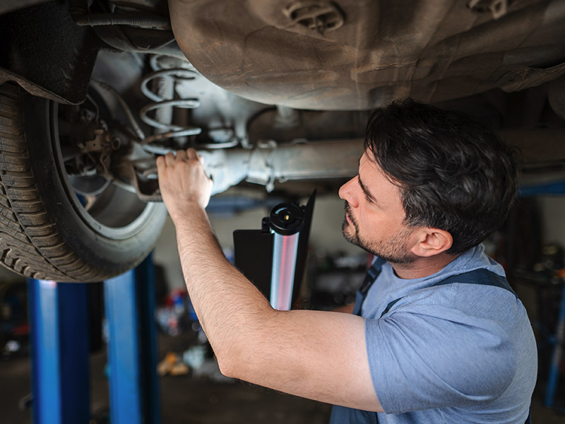 Auto mechanic working on suspension system of a car.