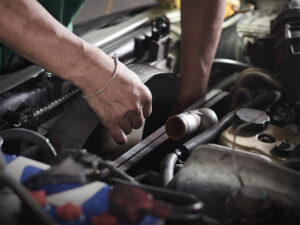 Auto mechanic working on the radiator of a car.