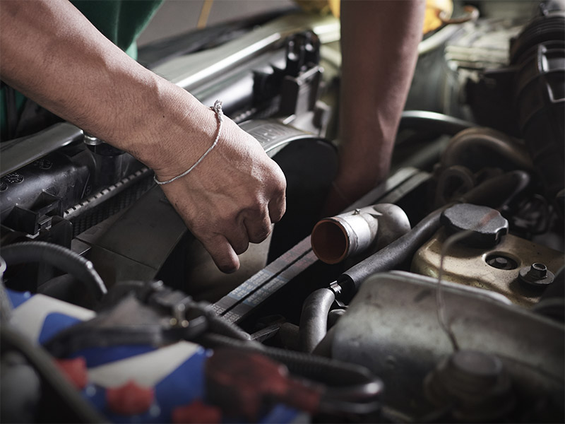 Auto mechanic working on the radiator of a car.